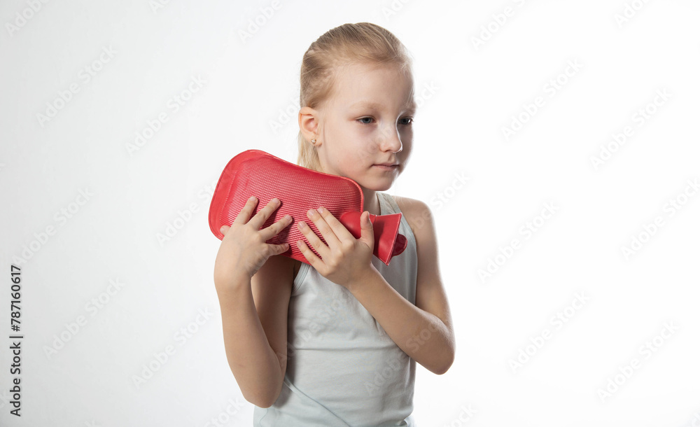 A little girl applies a heating pad with warm water to her shoulder joint for a sprained ligament. Heat treatment, close-up A little girl applies a heating pad with warm water to her shoulder joint for a sprained ligament. Heat treatment, close-up