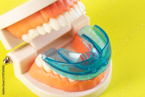 Therapeutic mouthguard on the background of a dental jaw mockup on a yellow background. Treatment of teeth grinding, bruxism in children and adults. 