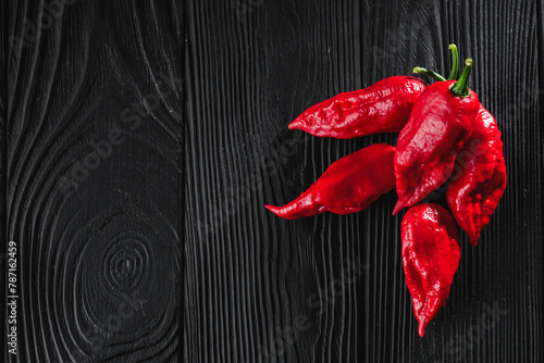 fresh red extra hot bhut jholokiya pepper on black wooden rustic background photo