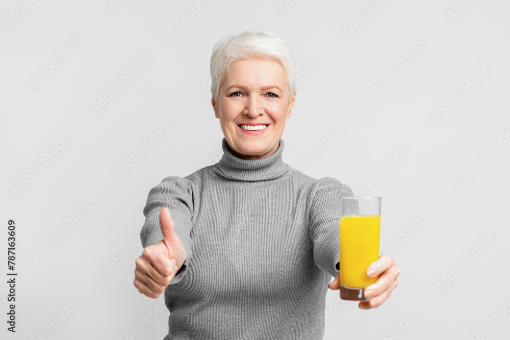 Happy senior promoting healthy drink with thumbs-up Happy senior promoting healthy drink with thumbs-up