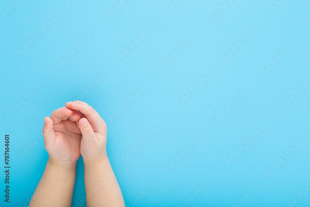 Baby boy opened palms on light blue table background. Pastel color. Closeup. Point of view shot. Empty place for text. Top down view. Baby boy opened palms on light blue table background. Pastel color. Closeup. Point of view shot. Empty place for text. Top down view.