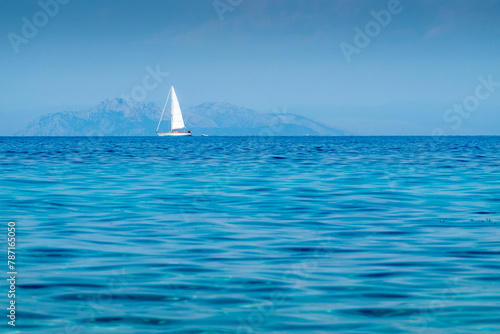 Views of the Mediterranean Sea and a white sailboat on the horizon, on the Greek island of Kefalonia.