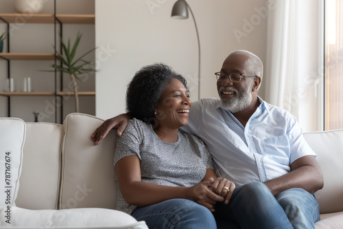 Happy adult couple sitting together on sofa in living room at home. Relaxiation, lifestyle concept