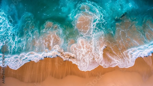 Top-down perspective of turquoise ocean waters gently lapping onto a golden sandy shore with foamy waves photo