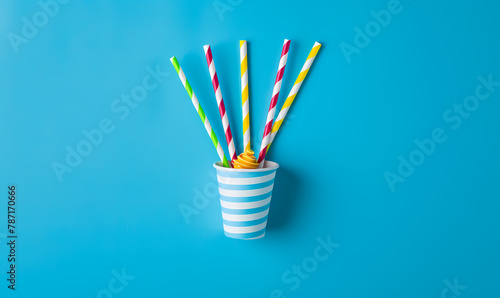 
Cornet with colorful drinking straws on bright blue background.