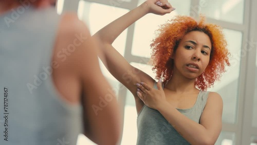 Sad young woman checking skin under her arm, irritated skin after depilation photo