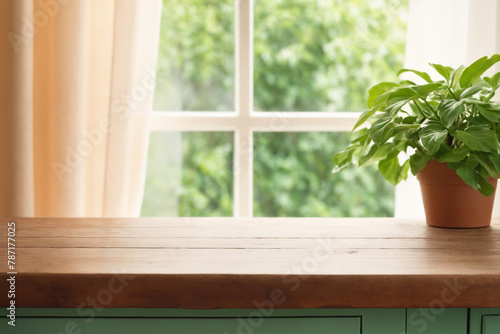 Wooden table top with green plant in pots on windowsill against blurred background. Side view with soft daylight and pastel color. Wooden table for mounting product and text placement.