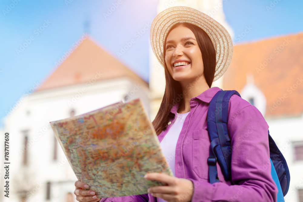 Fototapeta premium Tourist woman reading a map with excited expression