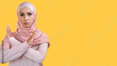 No gesture. Enough warning. Female protest. Confident serious dissatisfied woman in headscarf rejecting with crossed hands sign isolated on yellow empty space background. © golubovy
