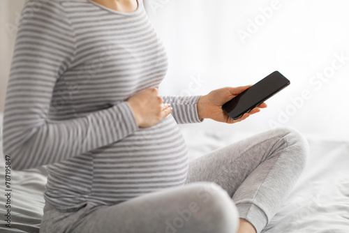 Close up of pregnant woman holding smartphone photo