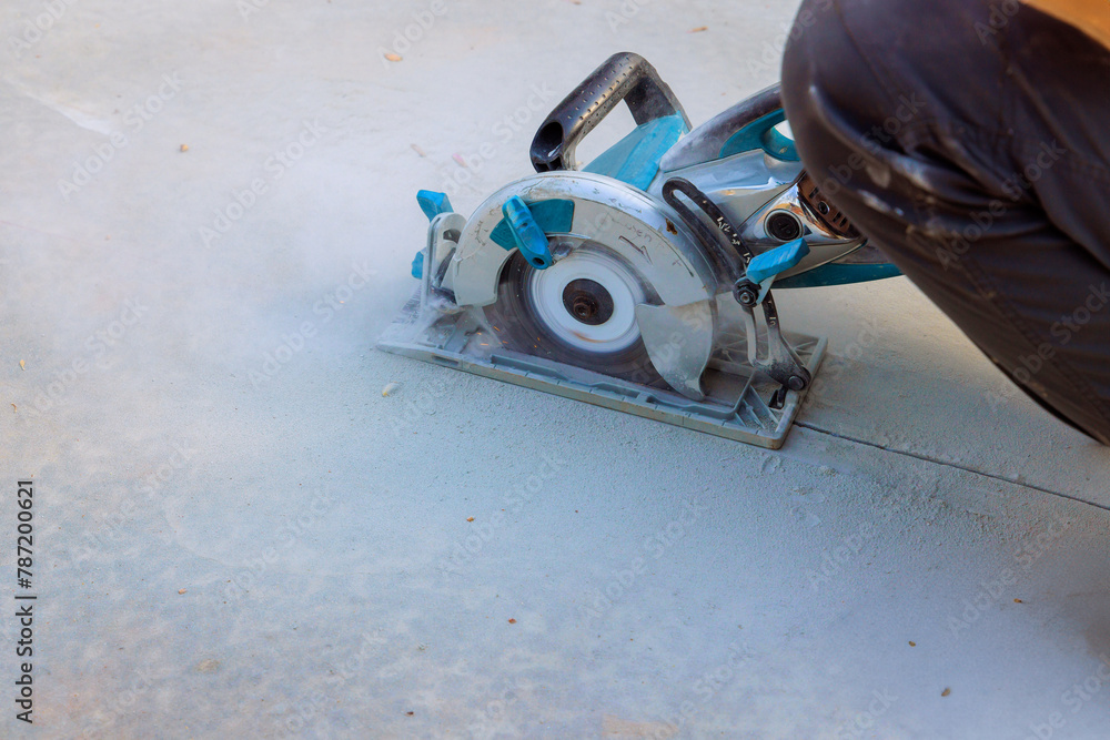 Using cutting machine grinder, construction worker cuts concrete foundations after they have been poured