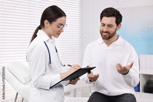 Doctor with clipboard consulting patient during appointment in clinic