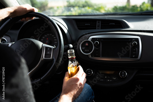 Tableau sur toile Driver driving a car with a bottle of alcohol in his hands close-up