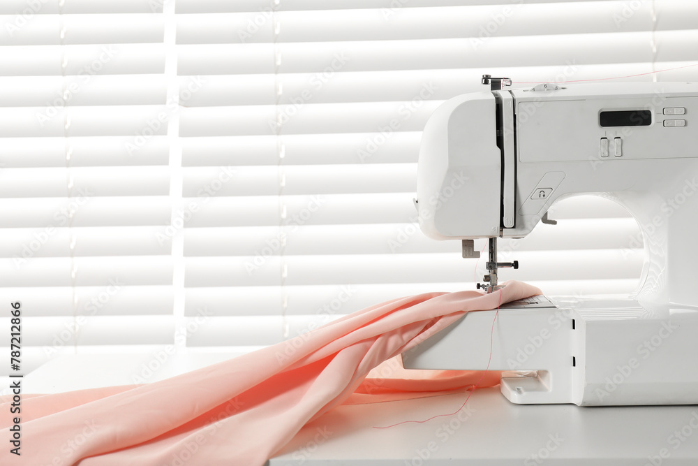 Sewing machine and fabric on white table indoors