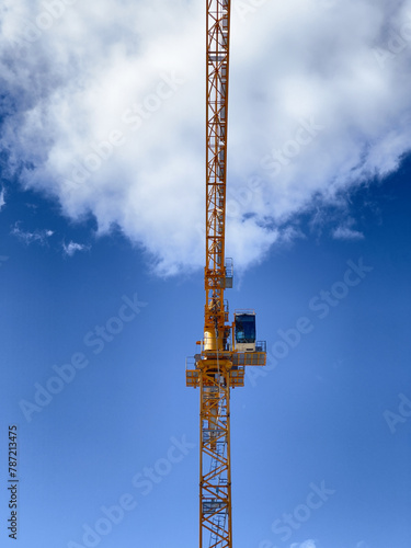 The arm of a construction crane seen en face against a blue sky