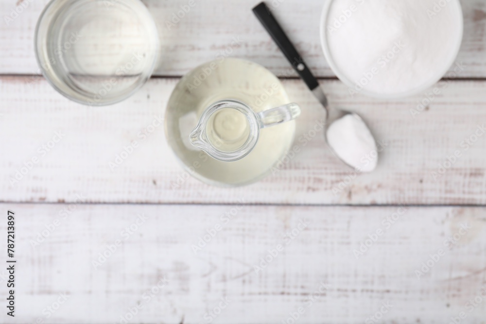 Fototapeta premium Vinegar and baking soda on white wooden table, flat lay. Space for text
