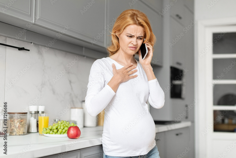 Pregnant woman with discomfort on phone, calling doctor Pregnant woman with discomfort on phone, calling doctor