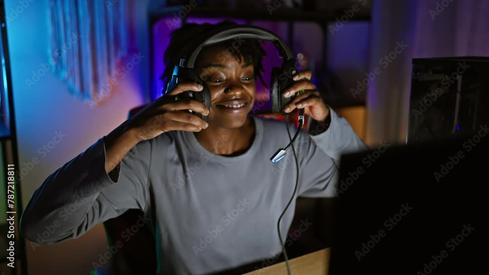 Young african american woman with dreadlocks enjoying gaming at home during nighttime. Young african american woman with dreadlocks enjoying gaming at home during nighttime.