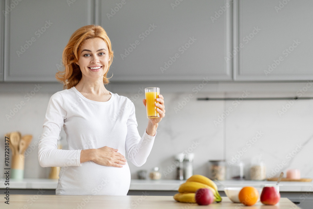 Pregnant woman drinking orange juice in kitchen Pregnant woman drinking orange juice in kitchen