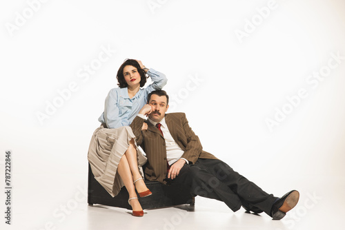 Young couple, man and woman in retro clothes sitting with bored faces isolated on white background. Concept of retro and vintage, fashion, relationship. human emotions, lifestyle