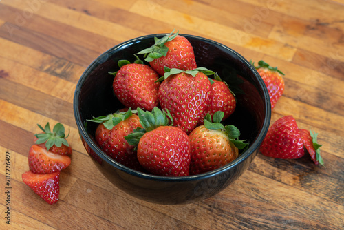 strawberries in a black bowl in a wooden background