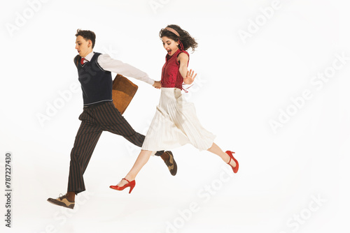 Happy young people, men and women in retro clothes holding hands and running isolated over white background. Concept of retro and vintage, fashion, human emotions, relationship