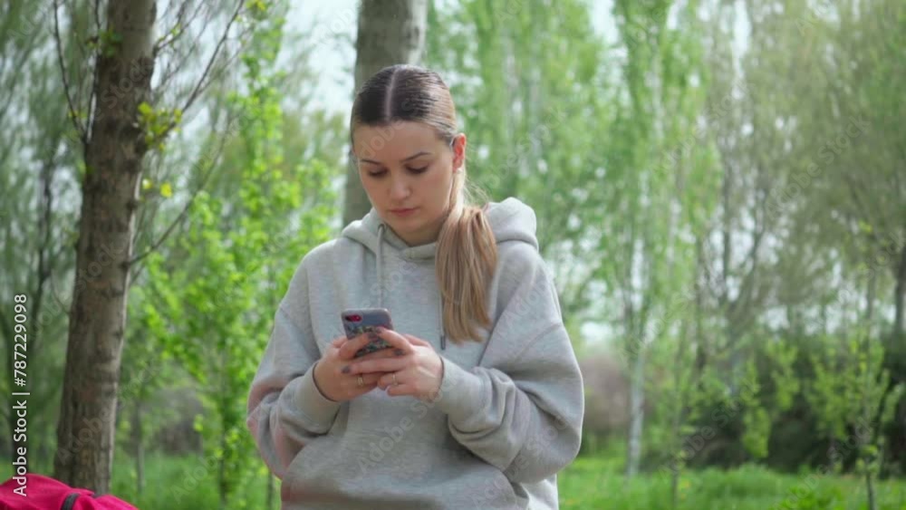 Girl resting during an excursion in nature looks at her mobile phone Girl resting during an excursion in nature looks at her mobile phone