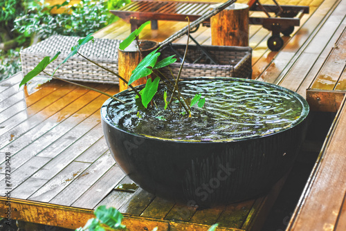 Rainy day. Beautiful view of wooden floor home balcony decoration with modern furniture in rain day. Cool and cozy home decor style. Lotus basin with water wave from rain and wetting floor look cool.