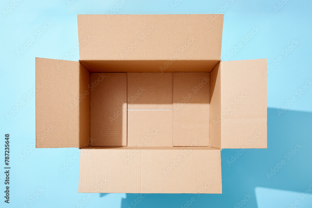 Overhead view of open empty cardboard box on blue background Overhead view of open empty cardboard box on blue background