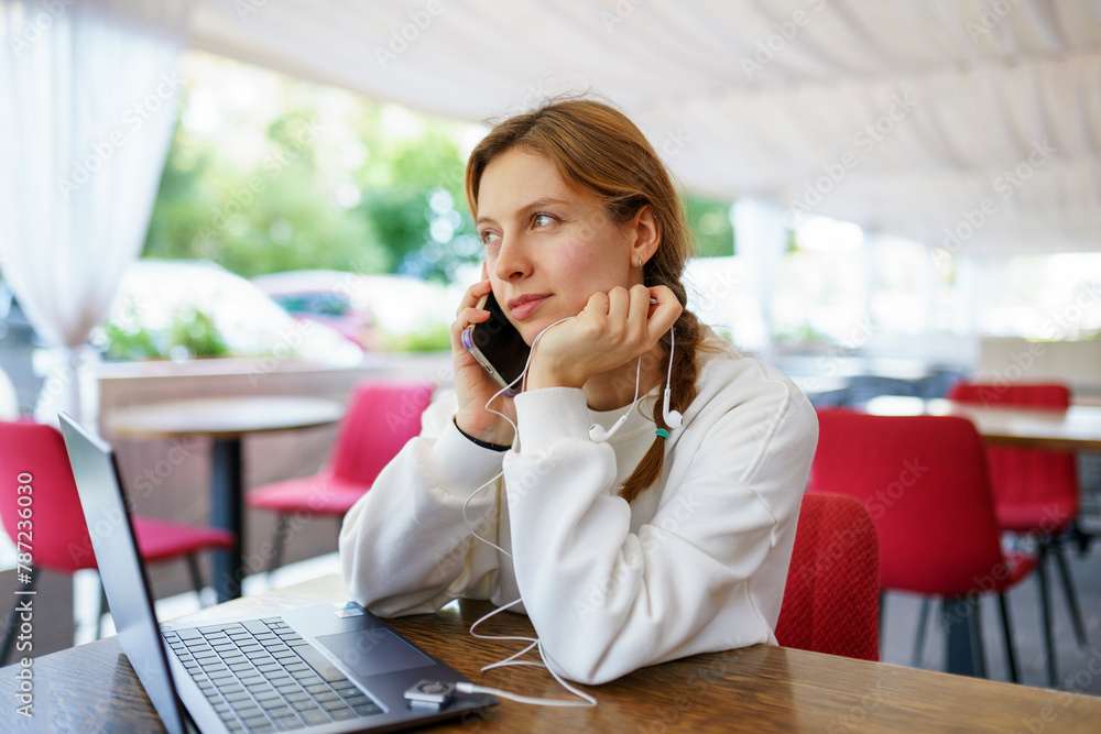 Woman with smart phone, headphones and laptop at cafe table Woman with smart phone, headphones and laptop at cafe table