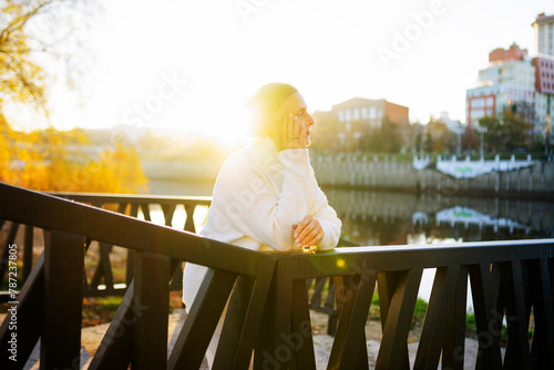 Woman in white sweater leaning on bridge photo