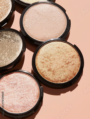 A variety of highlighter compacts cast shadows on a peach backdrop.