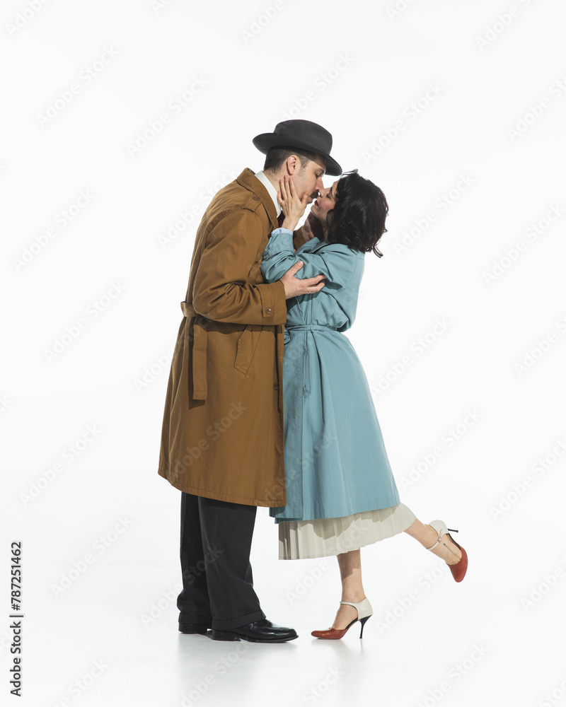 Portrait of happy young couple, man and woman in retro-style clothes, coats standing and kissing. Long-awaited meeting with beloved. Concept of retro and vintage, fashion, romance, relationship