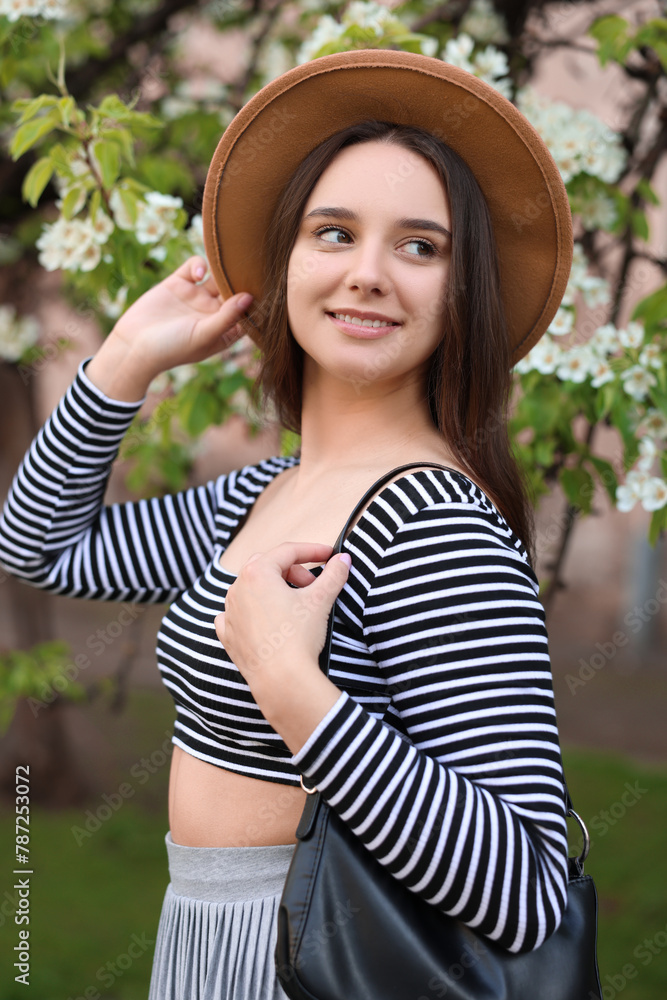 Fototapeta premium Beautiful woman in hat near blossoming tree on spring day
