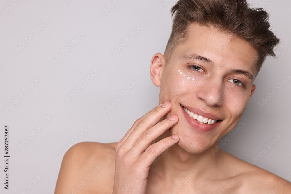 Handsome man with moisturizing cream on his face against light grey background. Space for text Handsome man with moisturizing cream on his face against light grey background. Space for text