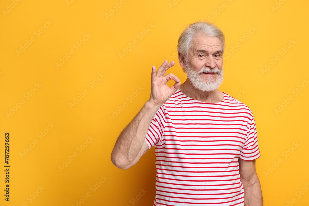 Senior man with mustache showing ok gesture on orange background, space for text Senior man with mustache showing ok gesture on orange background, space for text