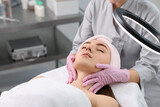 Cosmetologist making face massage to client in clinic, closeup. Space for text
