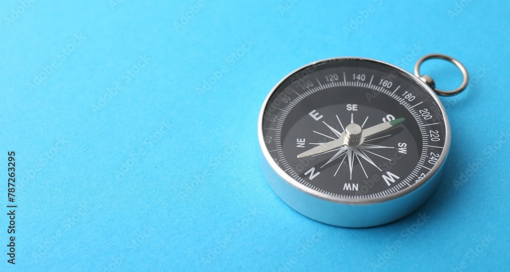One compass on light blue background, closeup. Space for text One compass on light blue background, closeup. Space for text