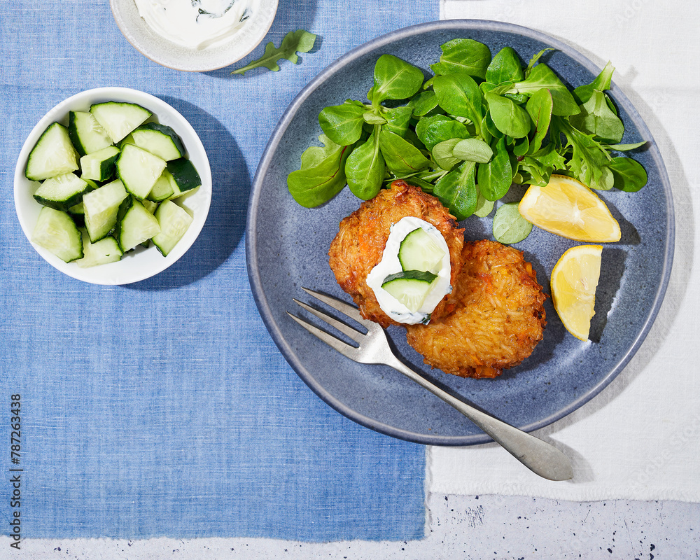 Spicy Veggie Rice Fritters. Salad of canons, Cucumber served with Fresh Cream and Lemon.Vegetarian food. Top view. Spicy Veggie Rice Fritters. Salad of canons, Cucumber served with Fresh Cream and Lemon.Vegetarian food. Top view.