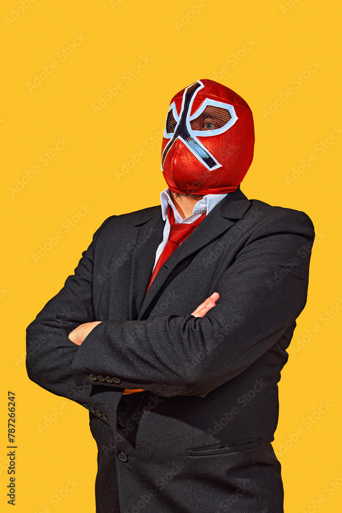 Portrait of confident man in wrestler attire with mask in official attire crossed hand on breast against yellow studio background. Concept of business as sport championship, motivation and goals. Ad Portrait of confident man in wrestler attire with mask in official attire crossed hand on breast against yellow studio background. Concept of business as sport championship, motivation and goals. Ad