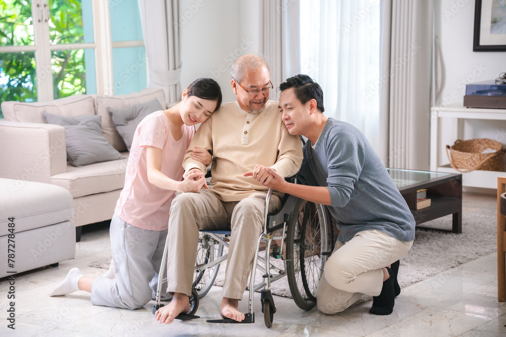 Happy elder Asian man using wheelchair while exercise indoor house with his son taking care of him at the retirement age with copy space Happy elder Asian man using wheelchair while exercise indoor house with his son taking care of him at the retirement age with copy space