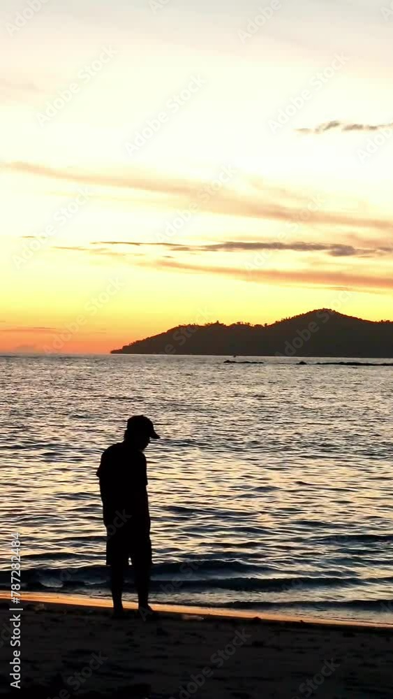 Silhouette of a Man Standing on the Beach at Sunrise Silhouette of a Man Standing on the Beach at Sunrise