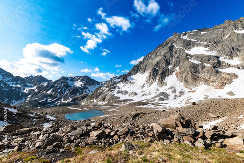 turquoise mountain lake surrounded by high alpine scree and snow fields