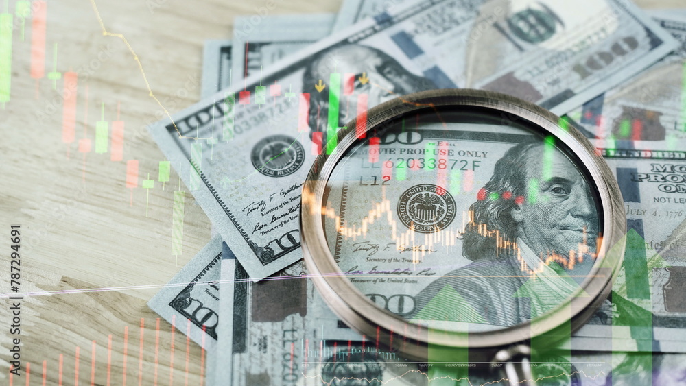 magnifier glass to focus Benjamin Franklin face on USD dollar banknote with stock market chart for analysis investment on currency exchange or forex and economy inflation concept. magnifier glass to focus Benjamin Franklin face on USD dollar banknote with stock market chart for analysis investment on currency exchange or forex and economy inflation concept.