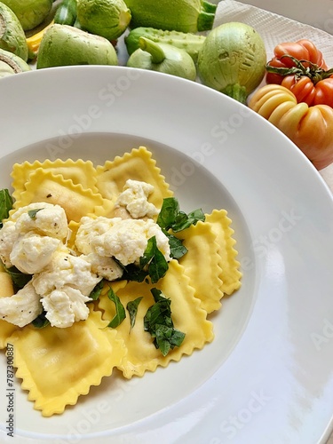plate with egg ravioli pasta, ravioli with crumbled mozzarella, plate with Italian dish, sliced basil
