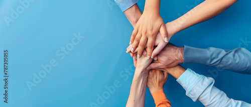 Capturing the essence of team spirit, a multi-ethnic group of individuals join hands in unity against a blue background photo
