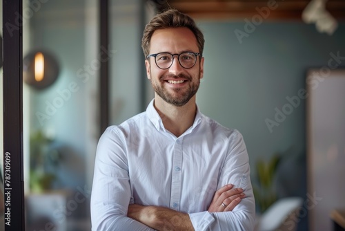 Portrait of a handsome smiling businessman standing with his arms crossed in a modern office, looking at the camera while wearing glasses and a casual outfit in the style of the copy space concept