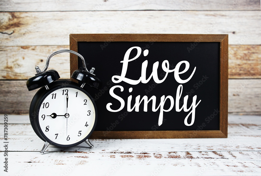 Live Simply Inspirational quote written on chalkboard with alarm clock Live Simply Inspirational quote written on chalkboard with alarm clock