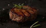 Grilled steak releasing steam, with aromatic rosemary and seasoning on a dark surface, showcasing the heat and flavor of the dish.