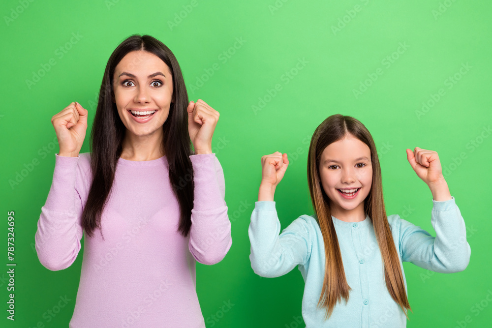 Portrait of two people mother daughter raise fists shout yes isolated on bright green color background - obrazy, fototapety, plakaty 